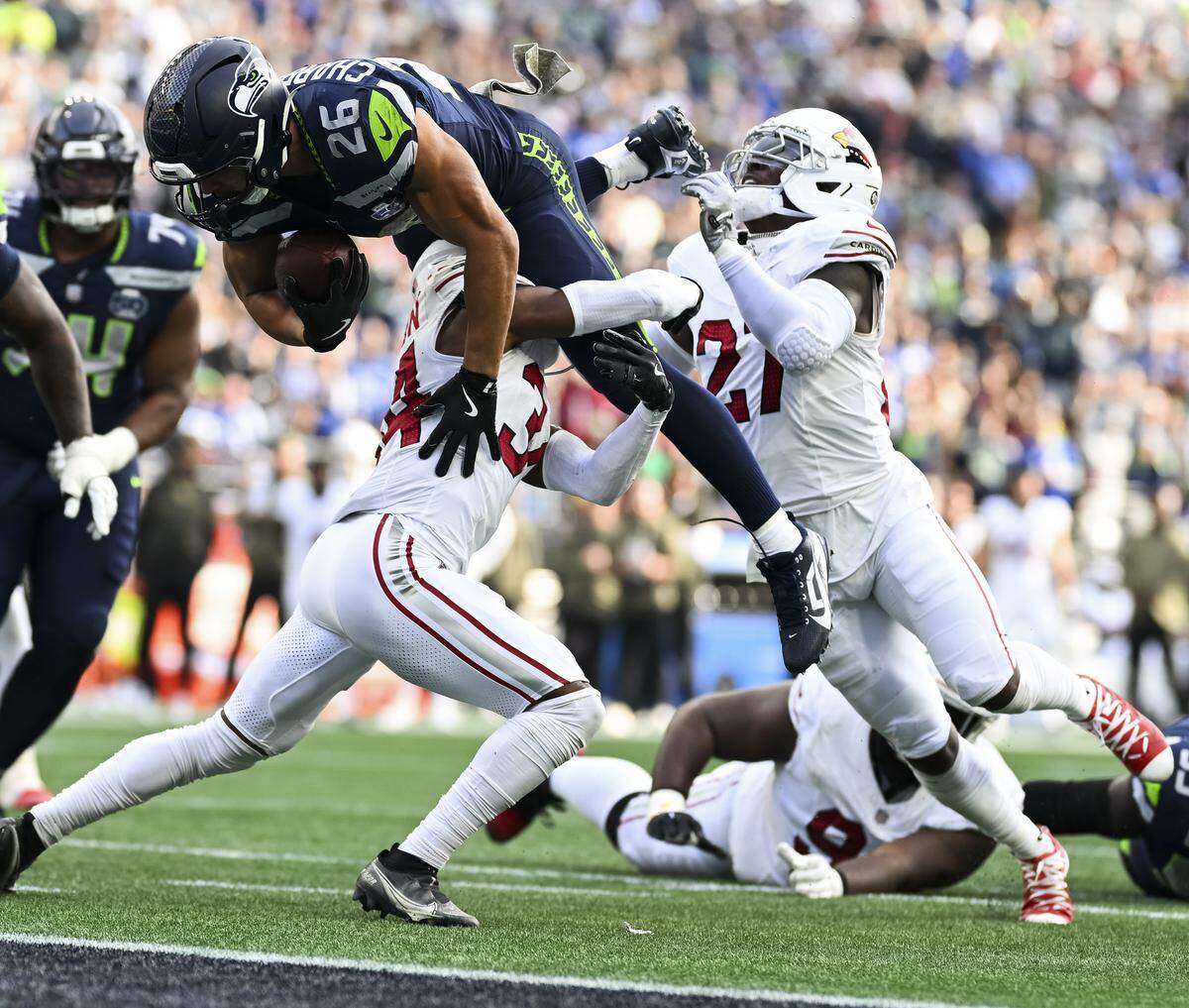 Seattle Seahawks running back Zach Charbonnet (26) gets airborne over Arizona Cardinals safety Jalen Thompson (34) as he scores a touchdown during the second quarter of the game at Lumen Field, on Sunday, Nov. 9, 2025, in Seattle.