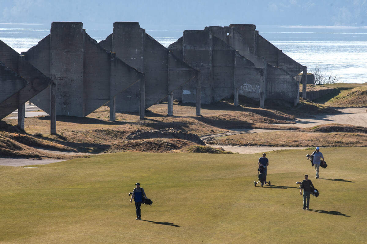 Golfers keep their distance while walking up the 18th fairway on Wednesday, March 18, 2020 at Chambers Bay in University Place, Wash.
