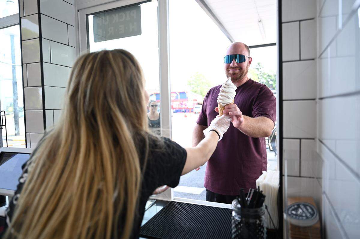 Kylee Fletcher, 19, of Enumclaw, hands a vanilla soft-serve ice cream cone to a customer at The Mount Rainier Creamery & Market on Friday, Aug. 2, 2024 in Buckley.