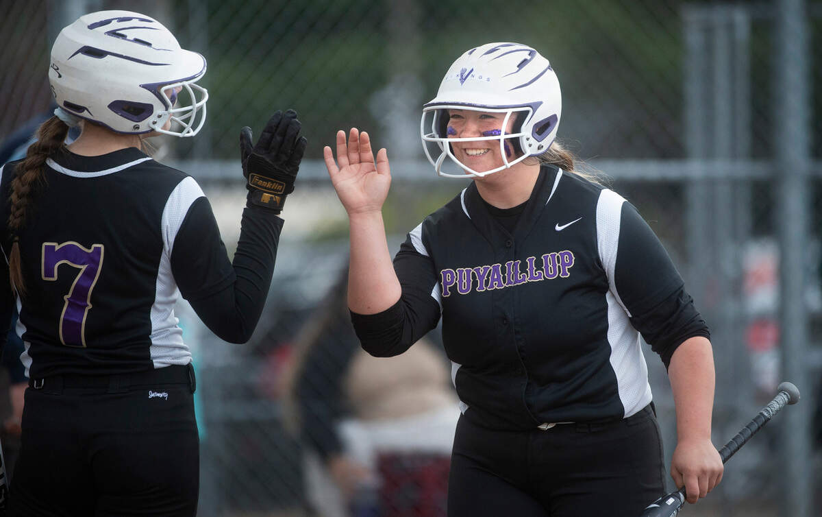 Puyallup designated hitter Taryn Takayoshi is welcomed to the dugout by teammate Sam Bland after scoring a run in the Vikings’ fastpitch game against the Sumner Spartans at Puyallup High School in Puyallup, Washington, on Wednesday, April 27, 2022.