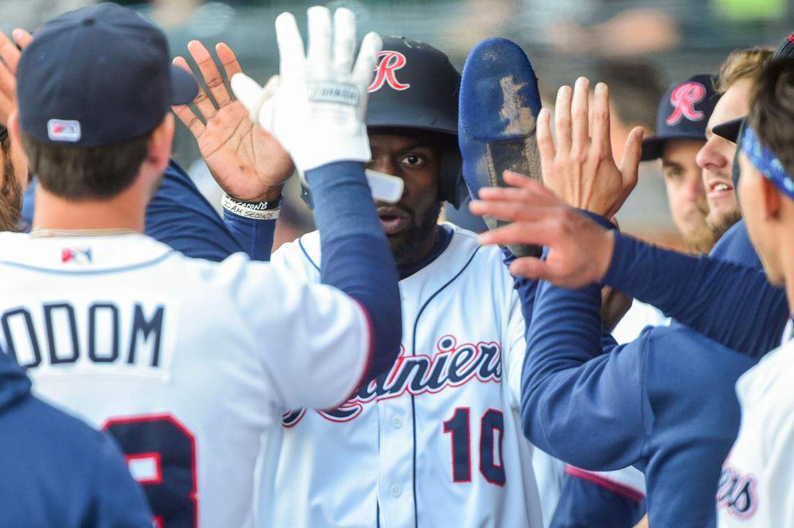 Tacoma Rainiers outfielder Taylor Trammell (10) gets high fives in the dugout after he scored on a Zach Green single in the top of the first inning of the season opener at Cheney Stadium in Tacoma, Wash., on Tuesday, April 5, 2022.