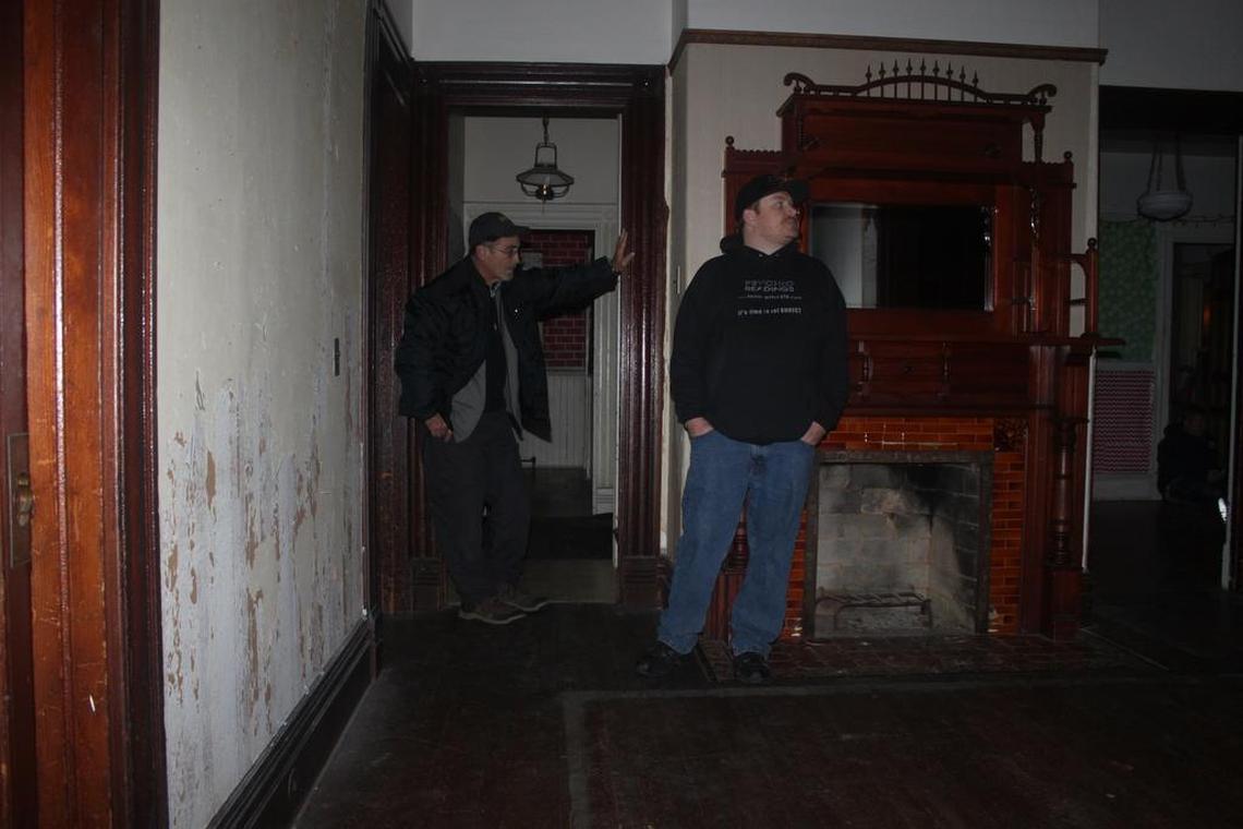 Peter Orbea, right, speaks to any non-living residents of the Walker-Ames house during a recent nighttime Special Paranormal Investigation tour. Richard, a tour participant, listens at left in a corridor reported to have paranormal activity.