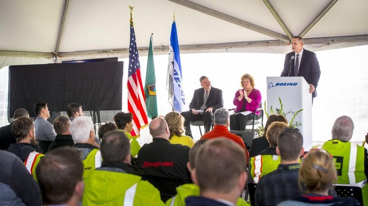 Boeing’s Jim Ockerman, vice president of Manufacturing and Safety for Boeing Fabrication, speaks to an audience of about 100 people gathered to celebrate the groundbreaking of the first new building to be erected on the Auburn site in nearly 25 years. Seated with him on the stage is Auburn mayor Nancy Backus and Boeing Auburn site Leader Jack Meehan.