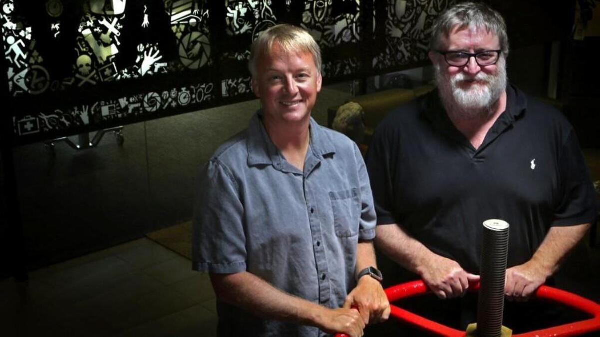 Valve executives Erik Johnson, left, and Gabe Newell stand near a stem valve that came from a submarine in the lobby of Valve’s headquarters in Bellevue last month. Gabe Newell is the CEO and co-founder of the company.