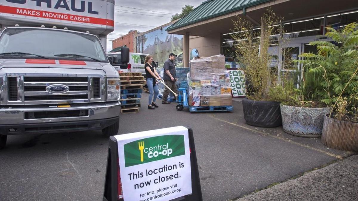 Central Co-op CEO Dan Arnett watches employee Shelby Alexander move merchandise to a moving truck at the closed Central Co-op in Tacoma on Monday.