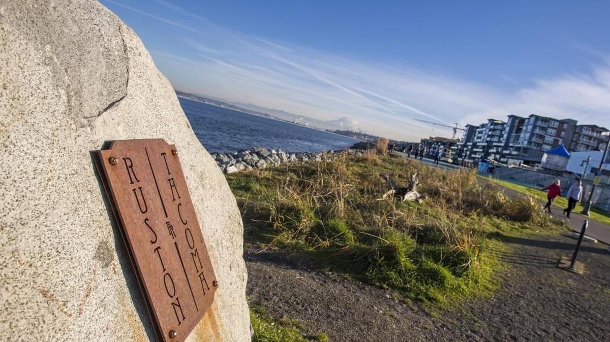 A rock with a metal sign shows where the border between Tacoma and Ruston meets the shoreline within the Point Ruston development.