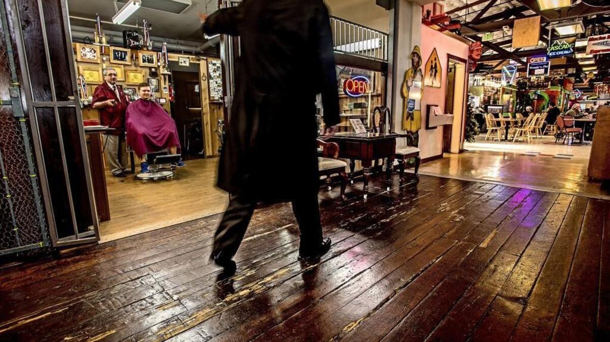 Pete Lira cuts a client’s hair at his shop Thursday inside Freighthouse Square. Compensation for lost business is part of the negotiation between WSDOT and the shopping complex.