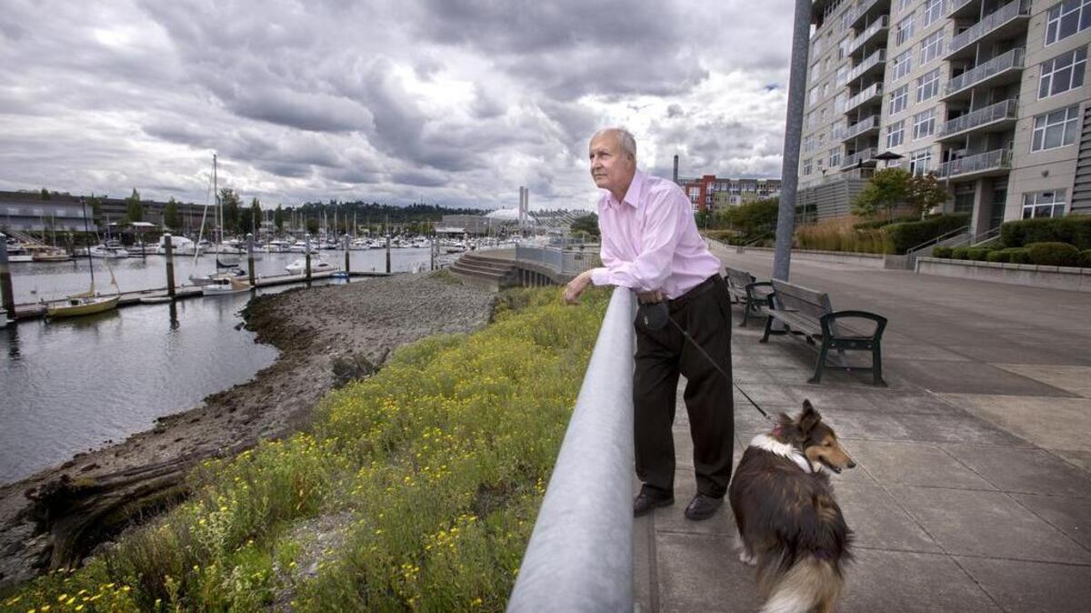 Foss Waterway Development Authority Executive Director Norm Gollub and his dog Charlie look over the Thea Foss area Tuesday where a hotel is expected to be built just west of him.