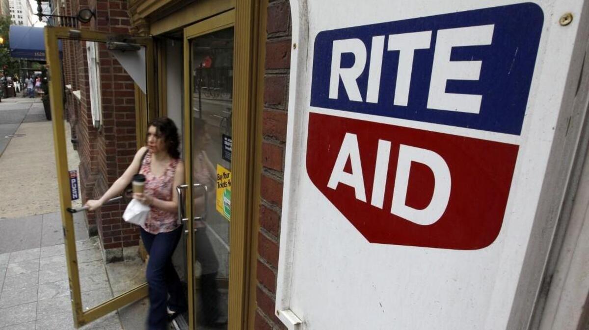 A woman exits a Rite Aid store, in Philadelphia. Grocery chain Albertsons is expanding through a deal to buy a portion of Rite Aid.