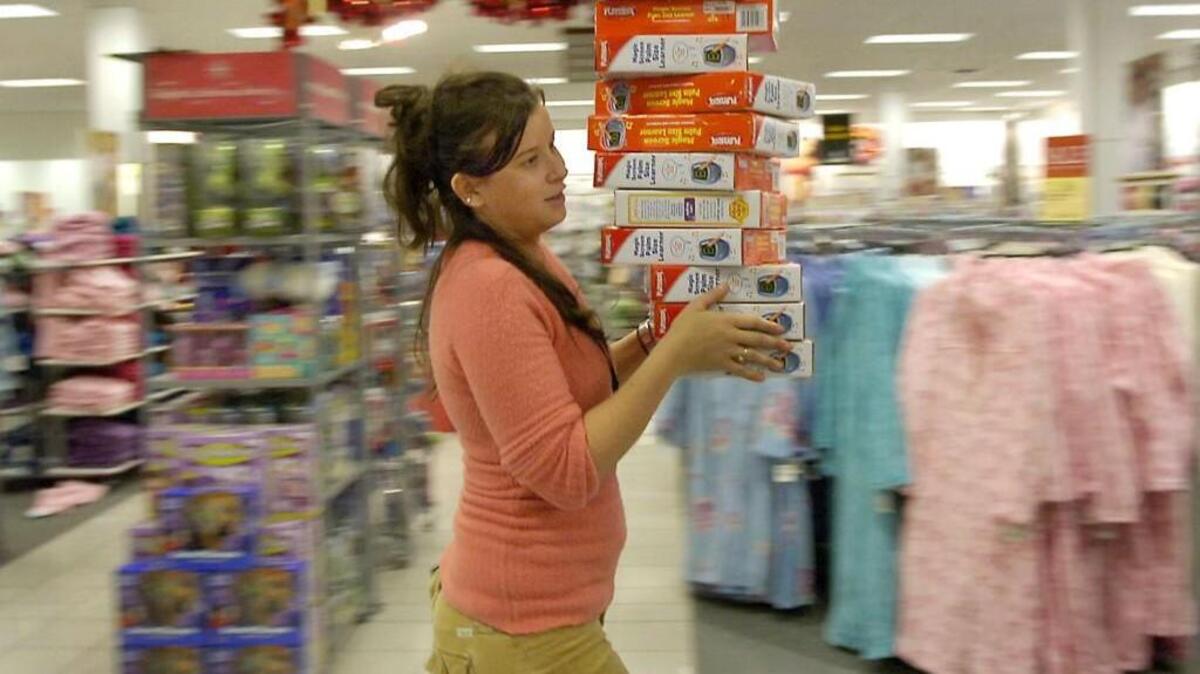 
A Kohl’s store associate carries a stack of toys for placement in their holiday display in 2008. 
