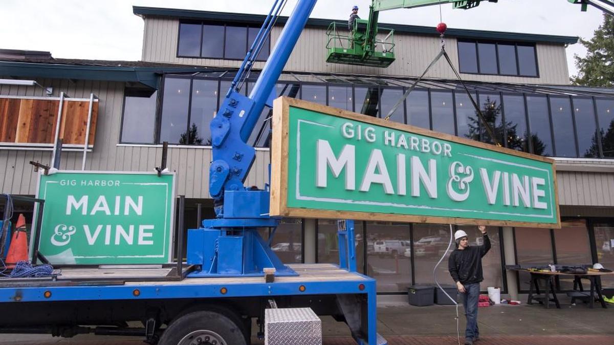 Workers erect signage for Main & Vine, a new Gig Harbor grocery store.
