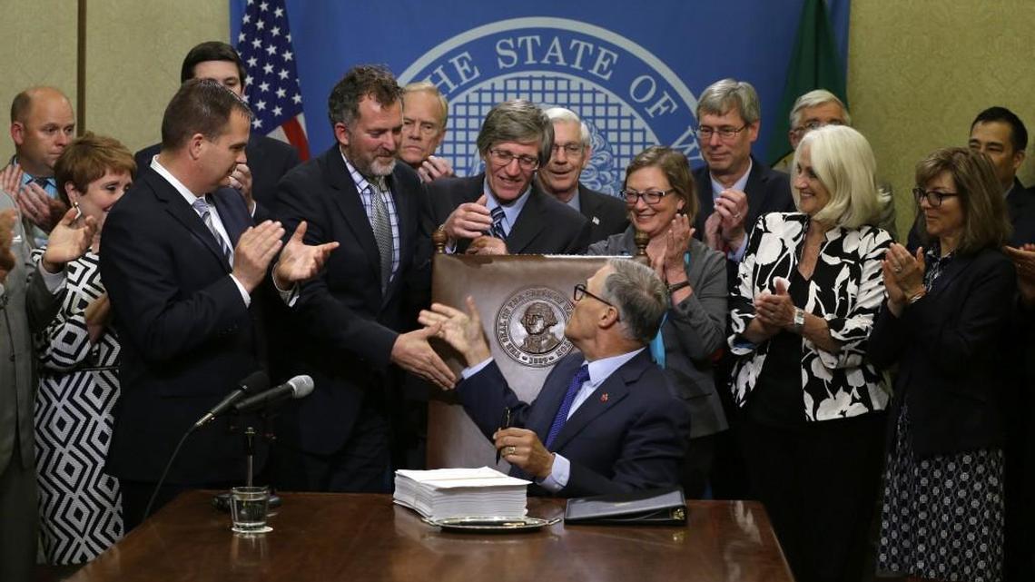 Washington Gov. Jay Inslee, center, shakes hands after he signed a new two-year state operating budget Friday, June 30, 2017, at the Capitol in Olympia. The budget was approved by the Legislature earlier in the day, just in time to avert a partial government shutdown.