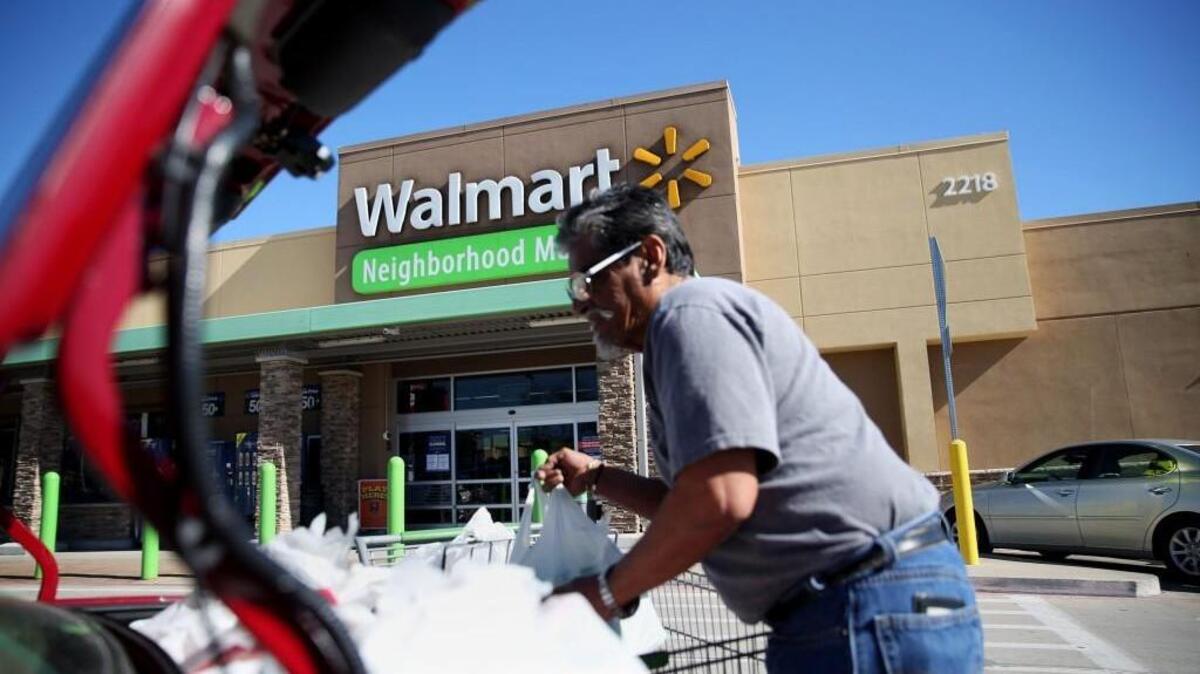 Richard Gutierrez loads groceries after shopping with his mother, Juanita Gutierrez, at the Wal-Mart Neighborhood Market in Dallas, Friday, Jan. 15, 2016. The Bentonville, Ark., company announced Friday the planned closure of 269 stores, more than half of them in the U.S. and another big chunk in its challenging Brazilian market.