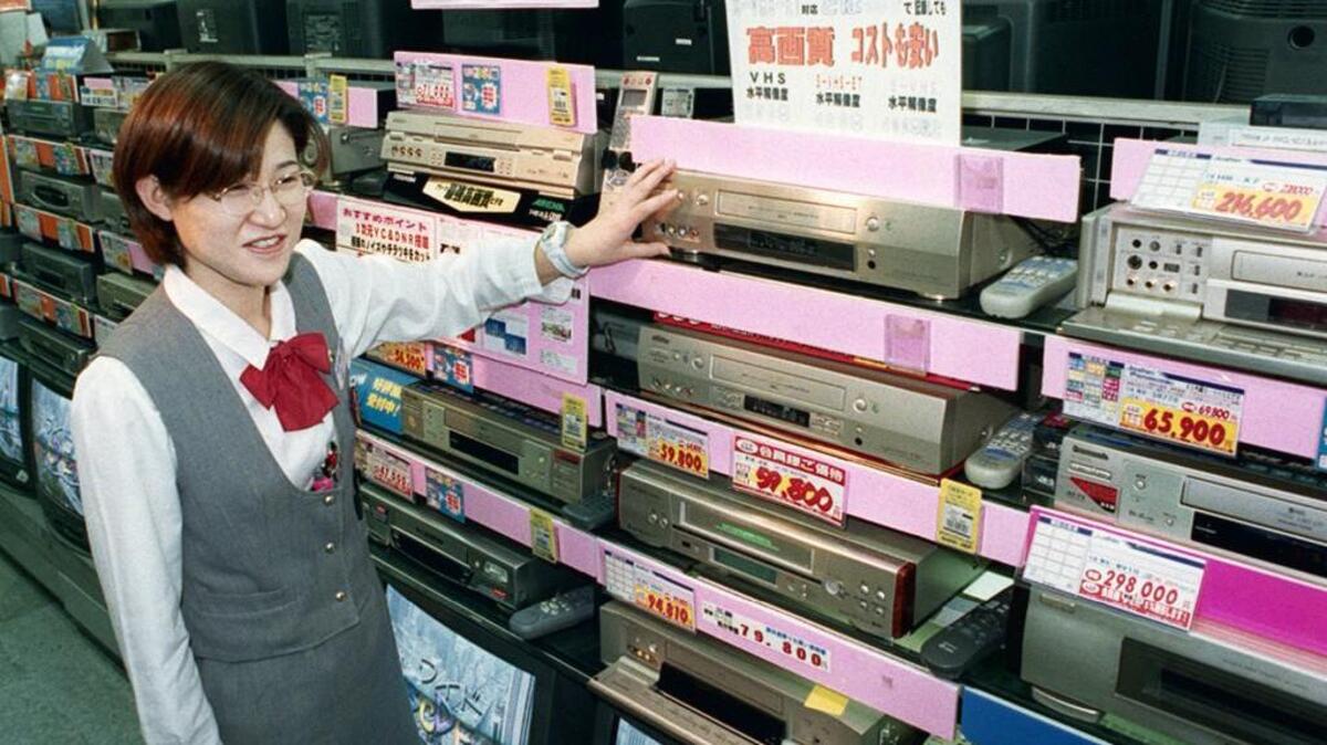 A sales clerk shows video casette recorders at a home and electrical appliance store in Osaka, Japan. Japanese electronics maker Funai Electric Co. says it’s yanking the plug on the world's last video cassette recorder. A company spokesman, who requested anonymity citing company practice, confirmed Monday that production will end.