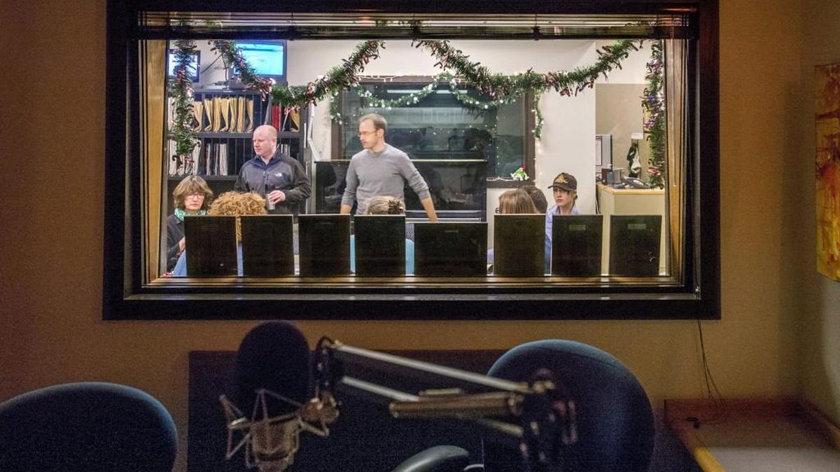 The news staff's morning meeting as seen from a broadcast studio in the Seattle offices of KPLU, December 21, 2015.