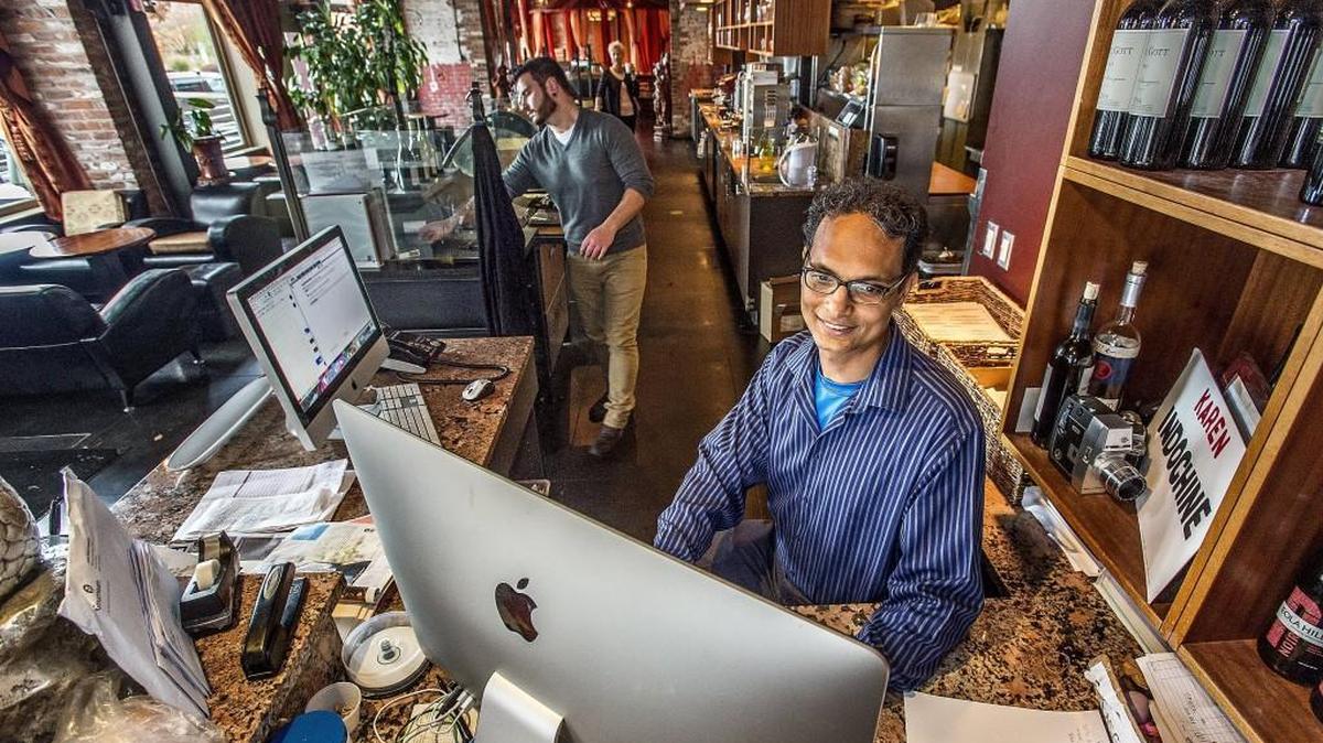 Russel Brunton, co-owner of downtown Tacoma restaurant Indochine, checks the day’s reservations while manager Samuel Kirbawy wipes down the gelato bar. Of Initiative 1433, which will raise the state’s minimum wage and make paid sick days a mandatory benefit, Brunton says: “Businesses will suffer, people will get laid off, businesses will close.”