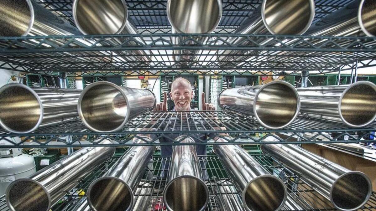 Tom Hoare, President of Green Air Supply is framed by stainless steel separation columns, part of wall mounted units the Tacoma company sells that extracts nitrogen from the air eliminating the need for nitrogen and mixed-gas cylinder deliveries for breweries , pubs and restaurants. Hoare, a biologist and former regional brewery Manager for the Ram Restaurant chain, was selected as the small business leader of the year for 2017 by the University of Washington Tacoma’s Milgard School of Business. Hoare, who is also exploring a business line that would allow coffee shops around the country to have a low-cost supply of nitrogen for cold brewed nitrogen coffee runs his business, with 8 employees from two garages behind Hoare’s North Tacoma home.