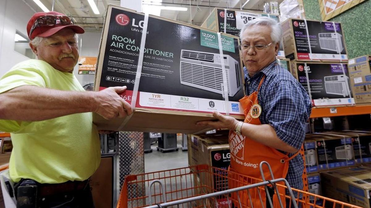 Store greeter Danny Olivar, right, lends a hand to a customer to heft an air conditioning unit from a rapidly declining stock at a Home Depot hardware store ahead of an expected heat wave Tuesday in Seattle. An excessive heat warning for the area began Tuesday afternoon and continues through Friday evening.