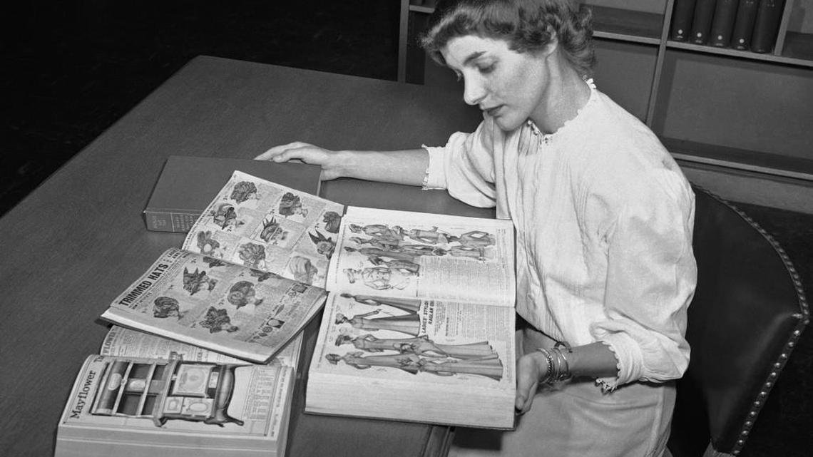 Ruth Parrington, librarian in the art department of the Chicago Public Library, studies early Sears Roebuck catalogs in the library's collection, in Chicago. The catalog Parrington is holding features women's fashion from 1902. The date of this photo is unknown.