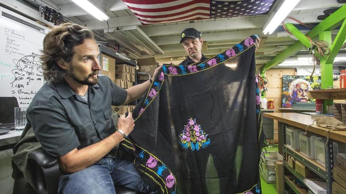 Former Army Ranger Matthew Griffin, left, and and brother-in-law Andy Sewrey, of Combat Flip Flops in Issaquah, show off a night vision black Sarong handmade in Afghanistan. Griffin will address chamber members Tuesday in the group’s annual luncheon.