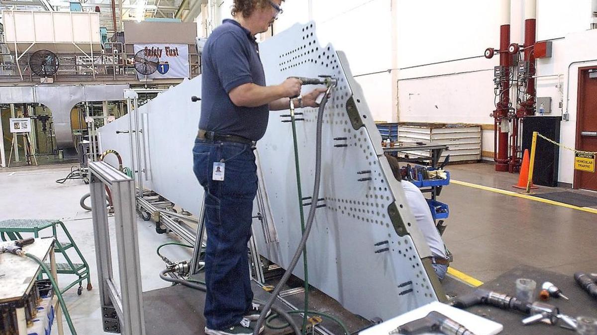 Assembly mechanics Frank Minnick, left, and Mike Halbert (partially hidden on right), attach fittings to a 777 vertical fin skin panel at the Boeing Federickson plant in 2004. As Boeing prepares to celebrate its 100th anniversary, officials recall talks that led to Boeing coming to Frederickson.