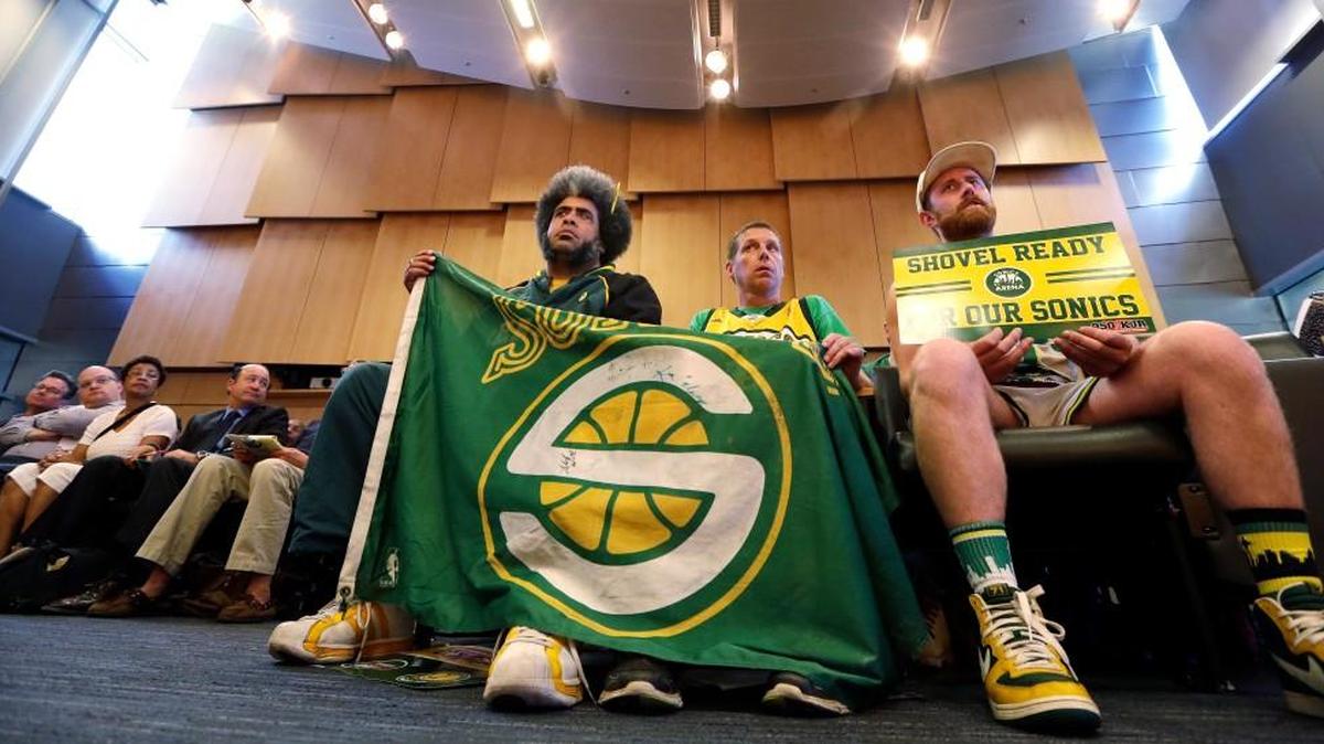 Fans of the defunct Seattle SuperSonics team, from right, Andrew Wergeland-Rammage, Kenneth Knutson and Kris “Sonics Guy” Brannon look on during testimony before the Seattle City Council on May 2, 2016, in Seattle. A vote on whether to vacate a stretch of road where an investor hopes to eventually build an arena that could house an NBA and NHL team was defeated 5-4.