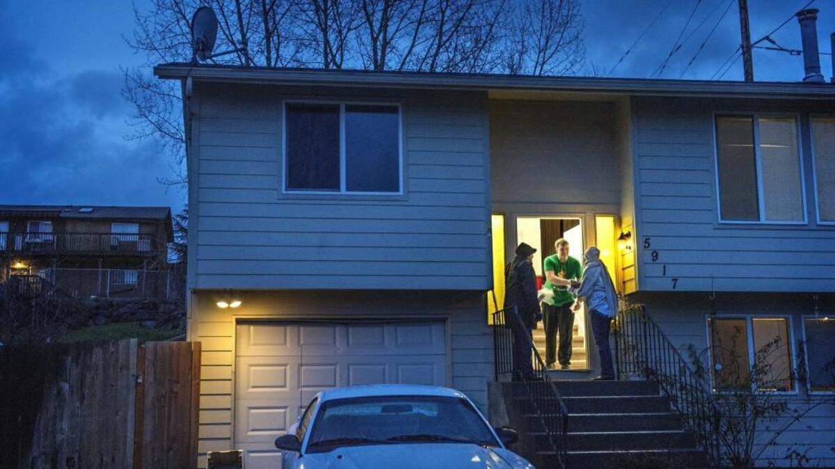 Daniel Smith and Sherrhonda Brown, of the Tacoma Urban League, introduce themselves to a homeowner, during canvassing of Tacoma neighborhoods in December. Smith and Brown were two of 17 people hired to canvass, connect and offer help in neighborhoods all over Tacoma as part of the Home Ownership and Mediation program.