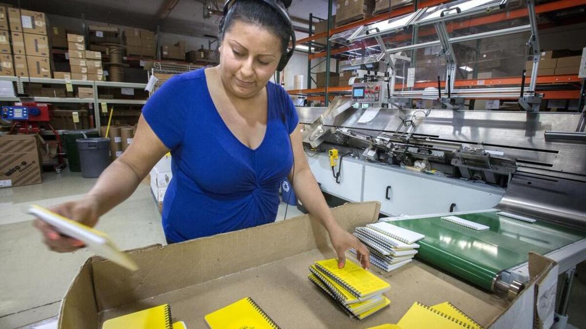 Rite in the Rain employee Sofia Gonzalez sorts notebooks after they were assembled by the spiral binding machine at the company plant in Tacoma last month.