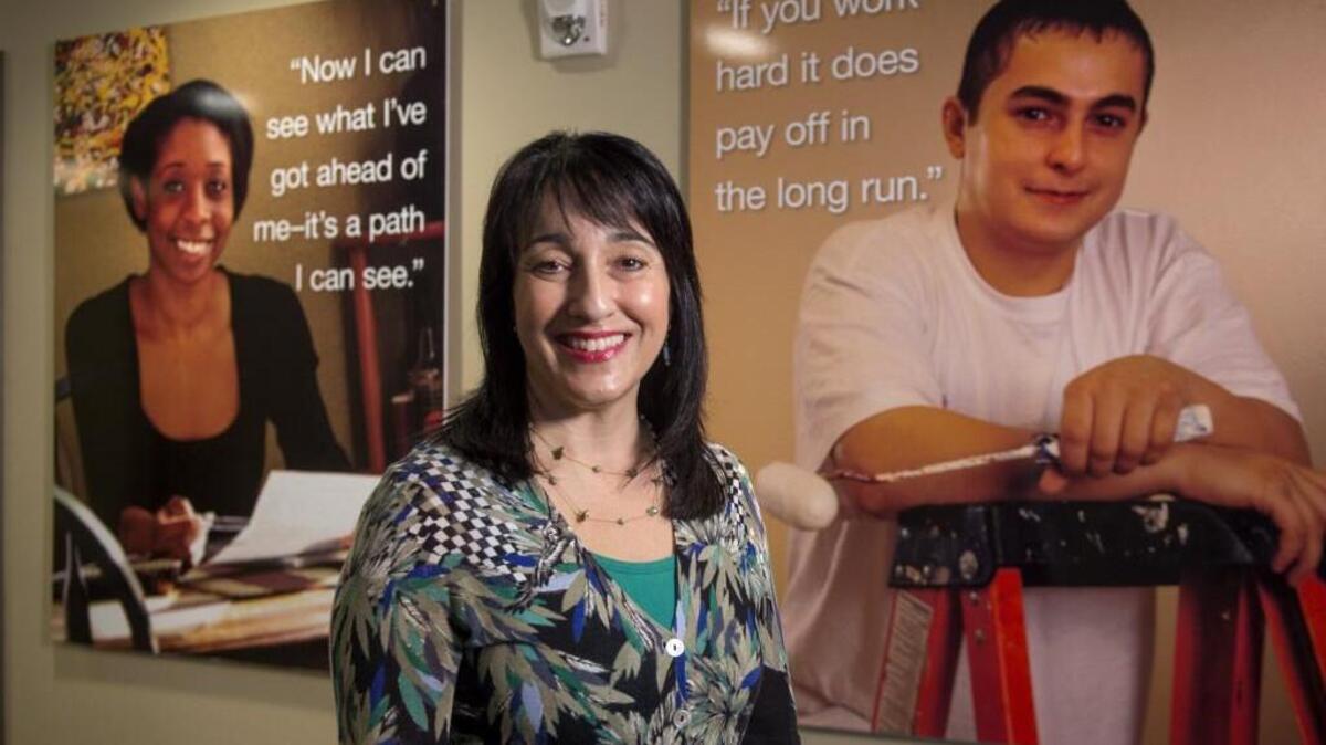 Lori Forte Harnick, the new CEO of Goodwill for the Olympics and Rainier regions, stands Monday with portraits of people helped by the nonprofit.