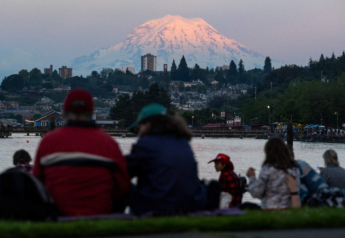 People sit along the Ruston Way Waterfront with a view of Mount Rainier in the background as they wait for the fireworks show to begin during Tacoma’s 4th of July Summer Blast in Tacoma on July 4, 2022.