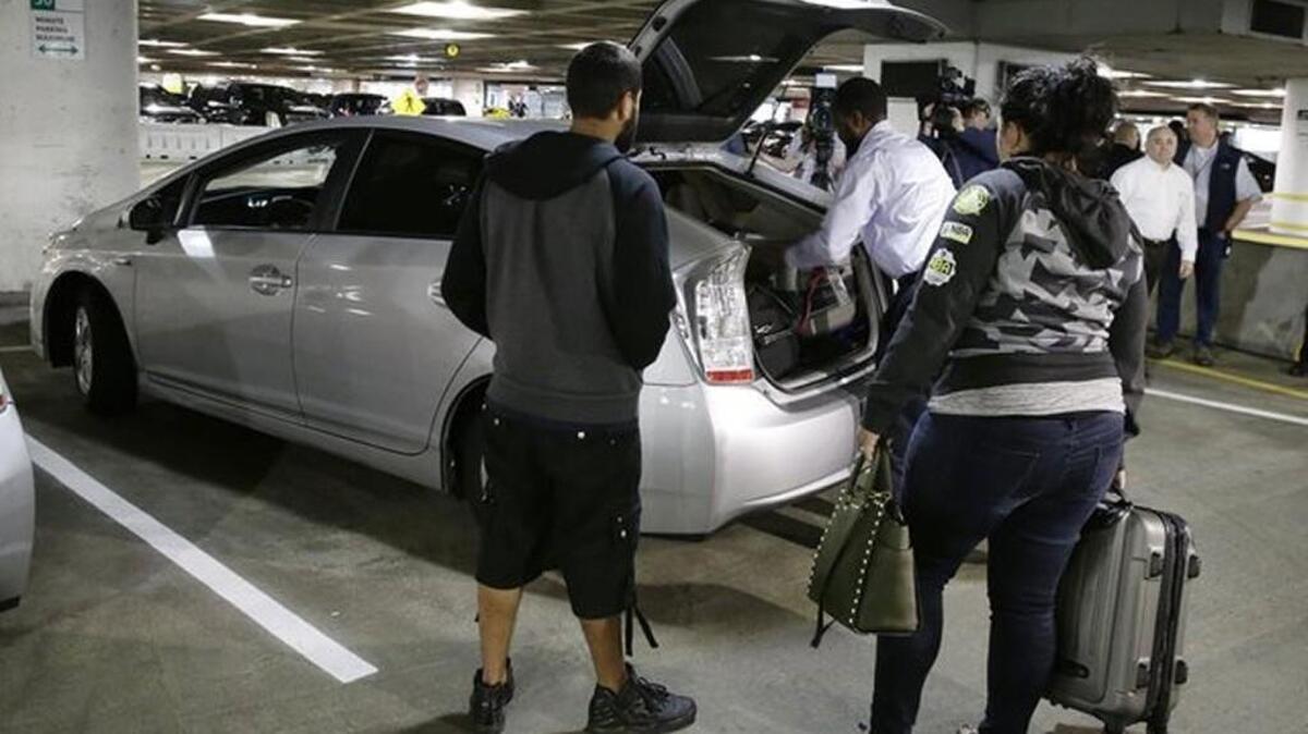 A driver for the Lyft ride-sharing service loads luggage into his vehicle as his customers wait at Seattle-Tacoma International Airport in March 2016. Costs to take Lyft or Uber from the airport are going up.
