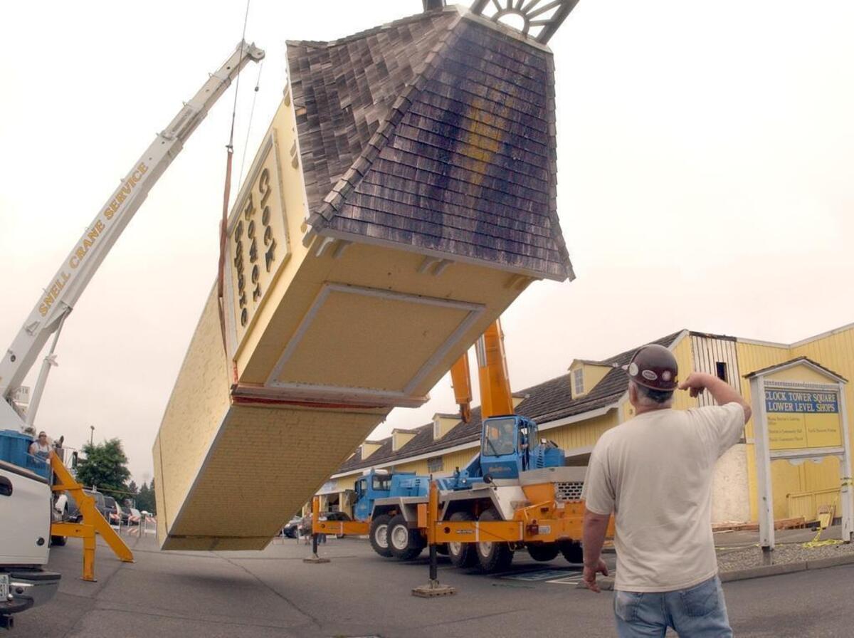 Superintendent from Snell Crane Service Denny Campanoli gives hand signals to two crane operators as they hoist the 40 foot clock tower horizontal for loading onto a flatbed truck. The structure was in the Clock Tower Square in University Place and was moved to 1125 Tacoma Ave. S., across from the Tacoma Main Library.