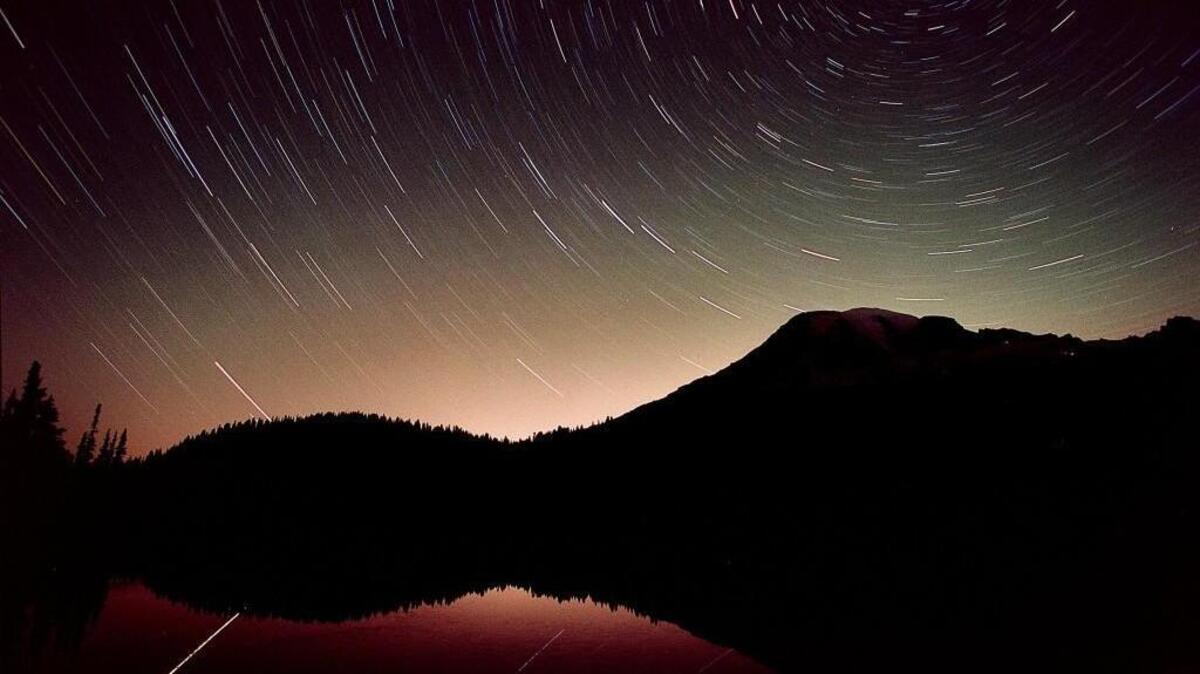 Mount Rainier stands in dark relief to the thousands of streaks of light (called star trails) representing the movement of the stars acrossed the night sky during a thirty minute exposure made at Mount Rainier National Park near Reflection Lakes on August 13, 2002.