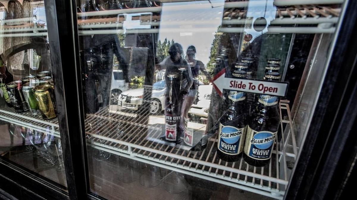 Customers walk inside Spring Lake Cafe in Fircrest Thursday May 12, 2016, reflected on the glass front of a cooler stocked with beer and wine. Today marks the first day beer/wine will be served in the section of Fircrest, Washington, where it was previously banned.