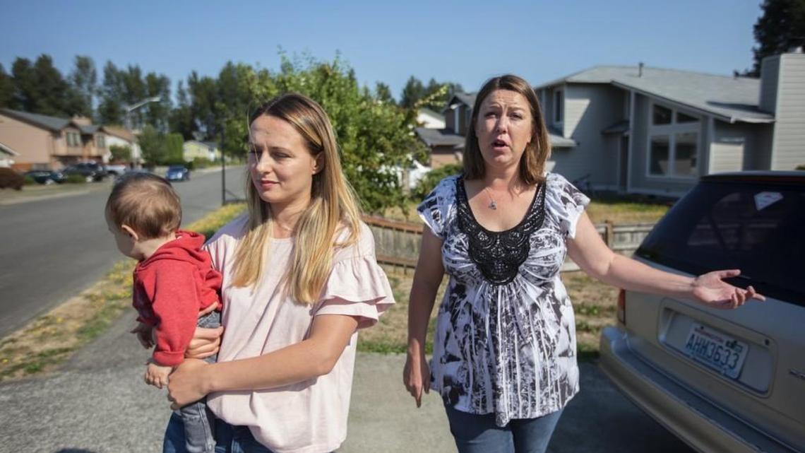 Anna Shtogryn holding her son Jonathan, 7 months, and Samantha Niemi live across the street from the Honey Bucket facility in Pacific. Both families are part of a lawsuit against the company. (Steve Ringman/The Seattle Times)