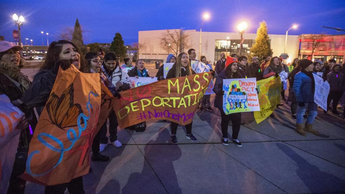 About 35 people chant and hold signs in downtown Tacoma on Friday night. They want to push Congress to vote to avoid deportation of non-citizen residents who have lived in the United States for most of their lives.