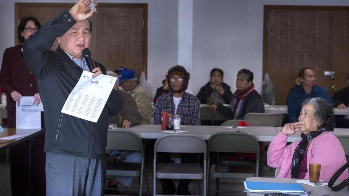 Darren Pen, a member of the Washington State Commission on Asian Pacific American Affairs, uses state identification to help Cambodians register to vote Tuesday at Holy Family of Jesus Cambodian Episcopal Church in Tacoma.