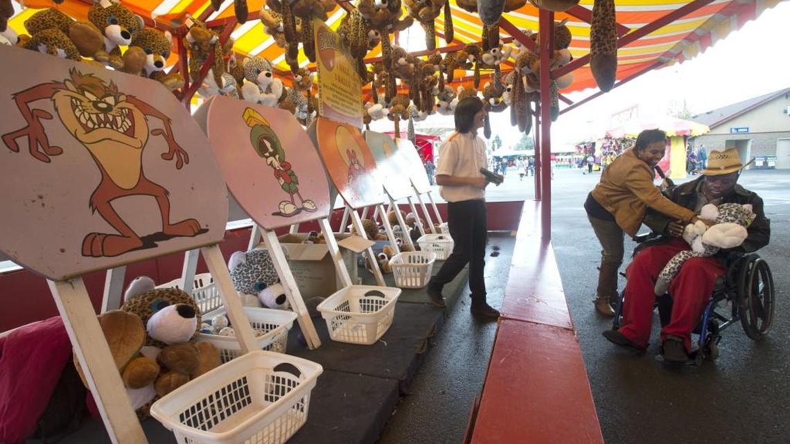 
Loretta Blanco gives a silly paw leopard animal she won at the Bank-A-Ball game to her husband, Anthony, at the Washington State Fair in Puyallup on Thursday. Funtastic employee James Legas, left, watches. The annual fair in Puyallup will run Sept. 2-25 next year.
