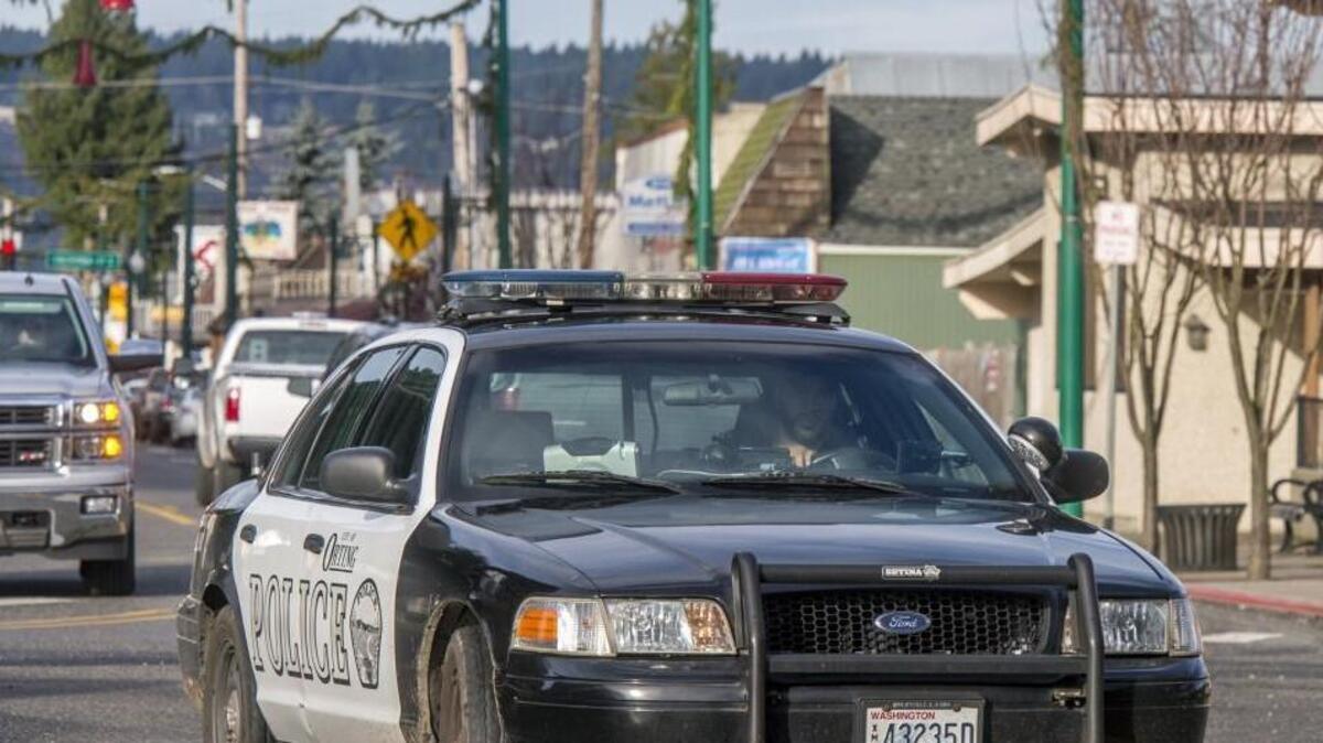 A police officer drives toward the Public Safety Building in Orting earlier this week.