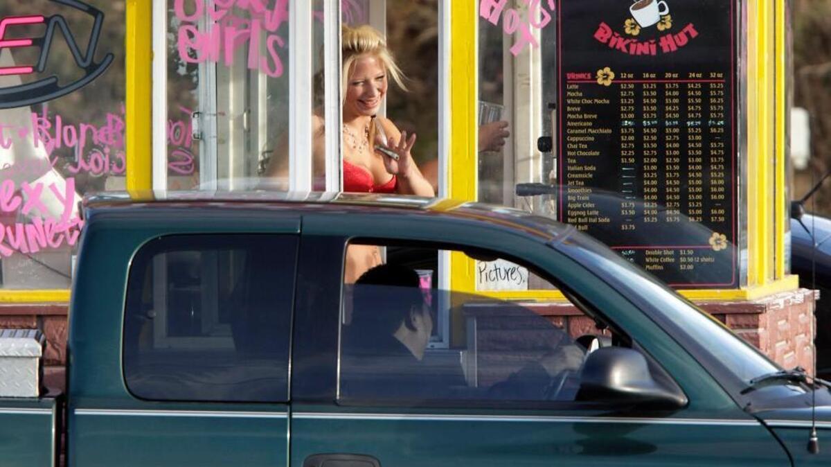 A barista at a Grab-N-Go Bikini Hut espresso stand holds money as she waves to a customer in 2010 just outside the city limits of Everett. Grab-N-Go was the focus of an undercover police investigation in 2009.
