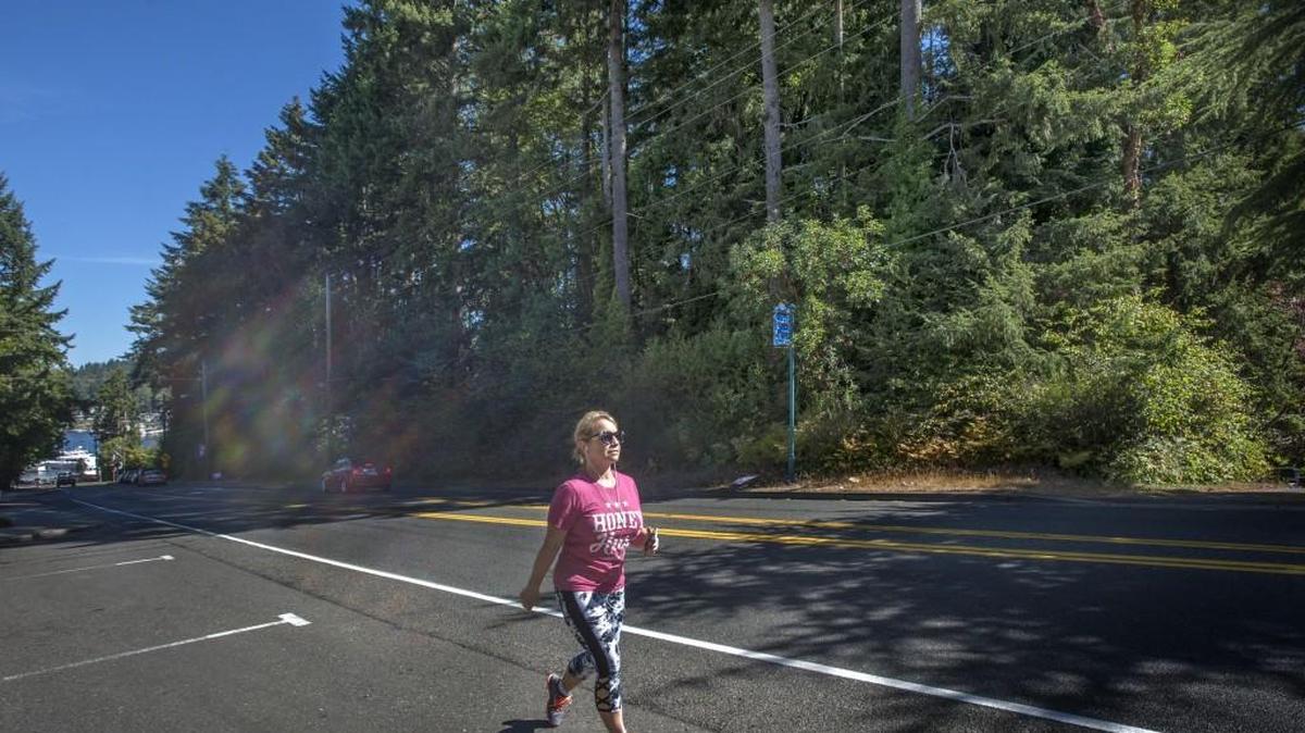 A woman exercises on Soundview Drive in Gig Harbor in 2016. The wall of trees to her left could be cleared to make way for 10 buildings that would hold 35 rental townhouse units under a development propsoal submitted to the city of Gig Harbor by the Ben B. Cheney Foundation. In back is Gig Harbor’s waterfront.
