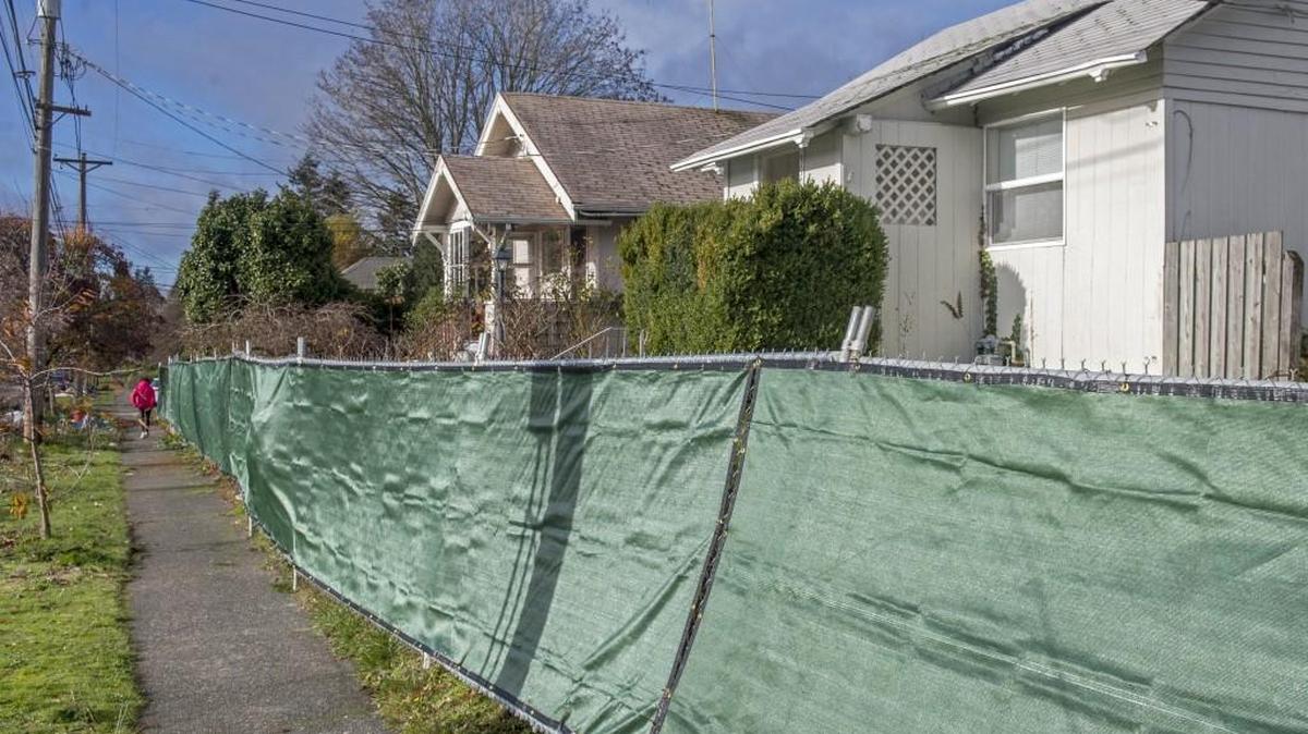 A fence surrounds houses and commercial buildings on North 25th Street, where a new development called Madison 25 will be built in the Proctor District.