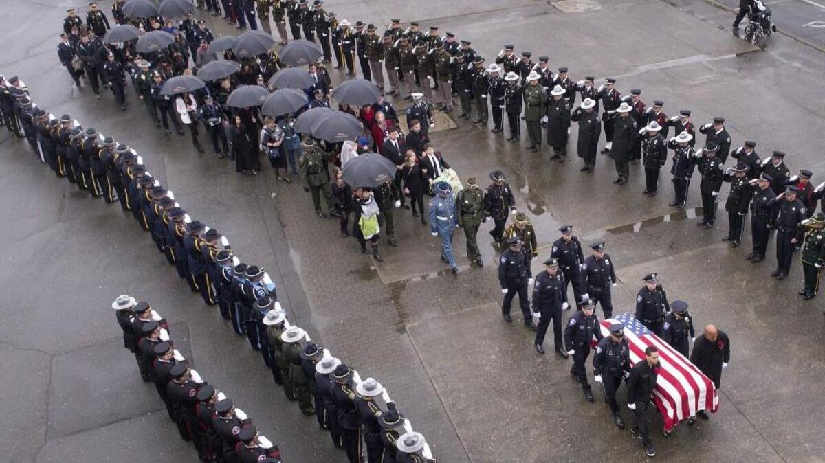 A casket bearing the body of Tacoma police Officer Reginald “Jake” Gutierrez is brought into the Tacoma Dome past lines of saluting officers from throughout the Northwest and beyond.