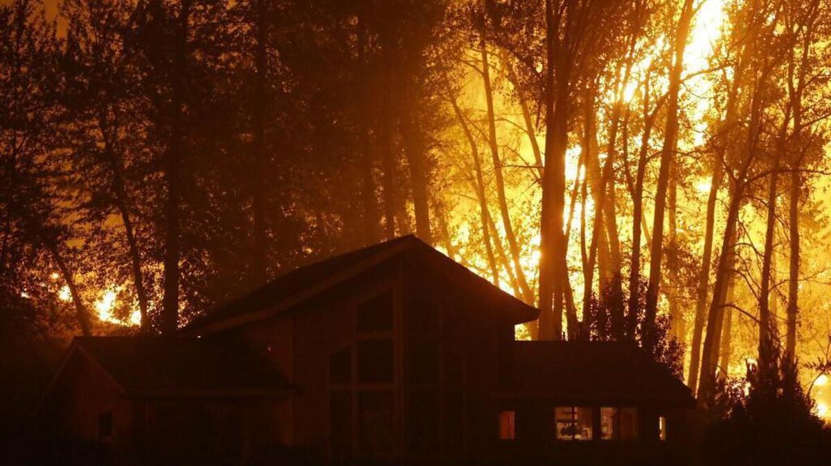 
A wildfire burns behind a home on Twisp River Road on Thursday in Twisp. Authorities on Wednesday afternoon had urged people in the north-central Washington town to evacuate because of a fast-moving wildfire. 
