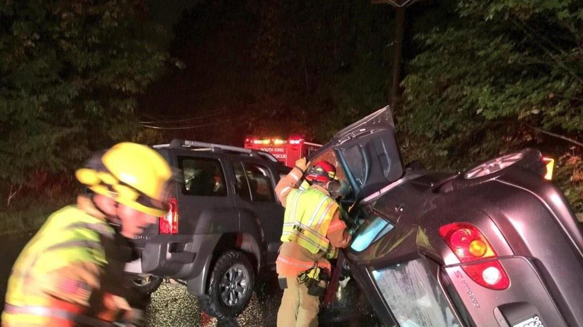 A firefighter peers into a rolled-over car Thursday night on South Dash Point Road in Federal Way. The driver of the car suffered minor injuries in the accident and was taken to an area hospital.