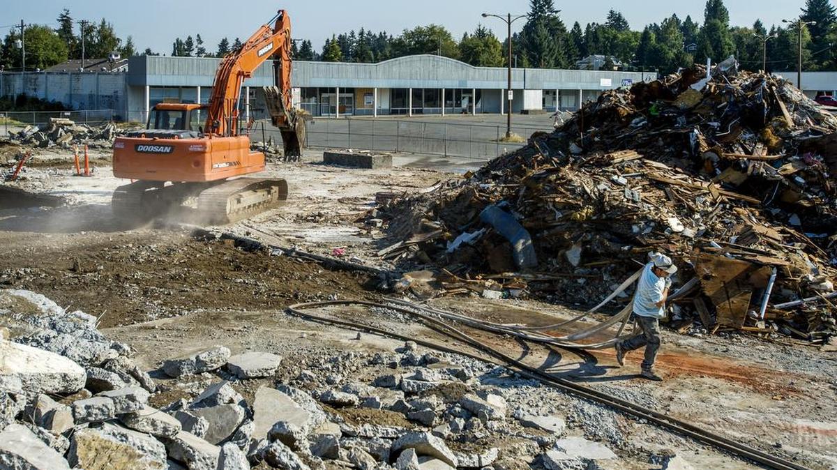 The former strip mall at 27th Street West and Grandview Drive West in University Place was demolished Sept. 12, 2014. Now a chainlink fence surrounds a mound of dirt that has remained relatively untouched for the last two years. The strip mall in the background has become an attratctive nuisance for vandals.