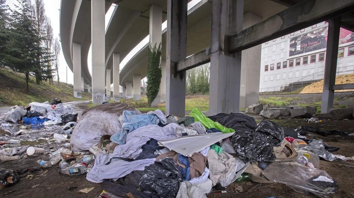A pile of trash builds up March 13 at the Tacoma Eastern Gulch under Interstate 705 at the East 26th Street bridge, east of the Brown & Haley factory, upper right, in Tacoma.
