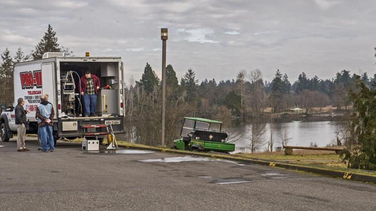 A crew packs up Tuesday after using special equipment to inspect sewer lines behind Pierce College in Lakewood. Sewage in Waughop Lake, right, at Fort Steilacoom Park might be coming from the lines.