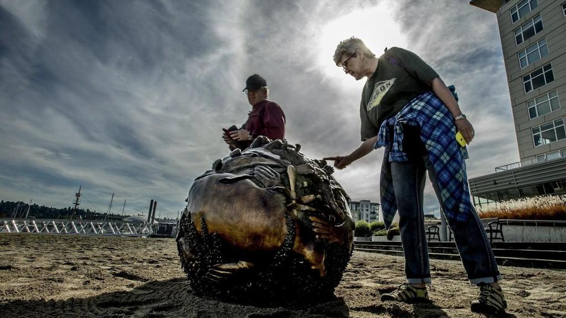 
Joyce and John Ribble, of Indianapolis, Indiana, examine up close a newly installed work of art by Tacoma artist Ed Kroupa. “I think they are wonderful,” said Joyce Ribble of “Floating Life Forms,” a series of six bronze spheres that depict marine life native to the Puget Sound.
