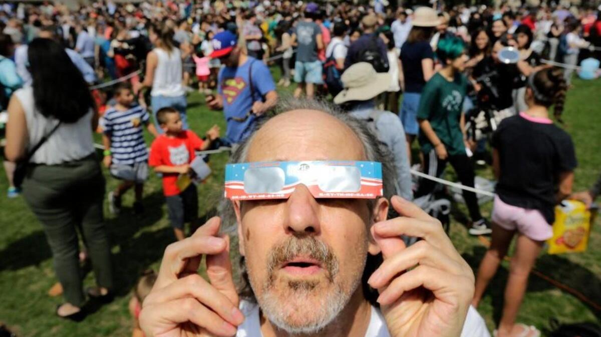 Robert Arthur, of Watertown, Mass., uses protective eclipse glasses on Monday. He probably could use some tips for recycling or reusing now.